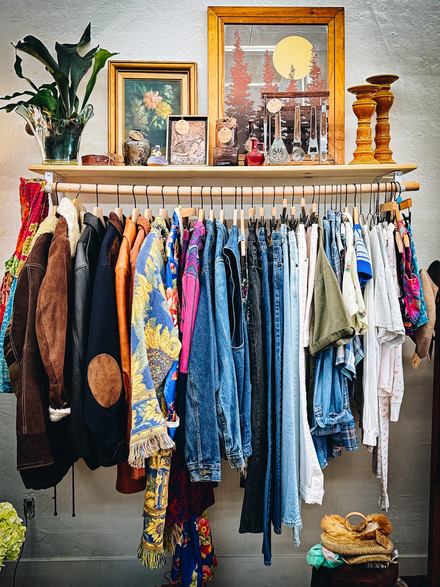 Clothing rack with various garments against a wall with decorative items